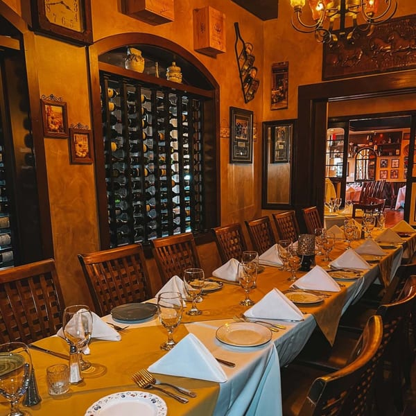 A long dining table set with white napkins and glasses in Cafe Vico's warm, Italian-themed interior.