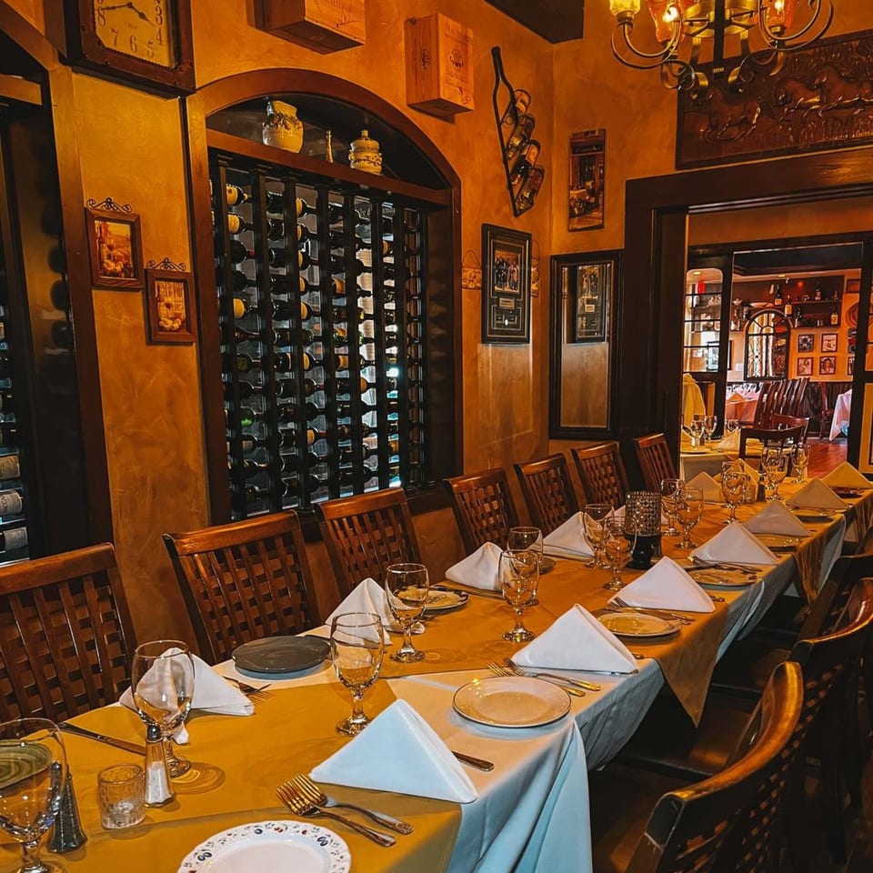 A long dining table set with white napkins and glasses in Cafe Vico's warm, Italian-themed interior.