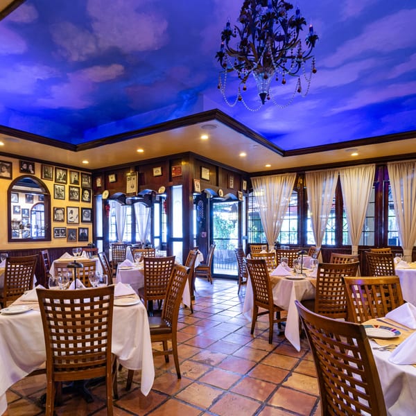 Cafe Vico's dining room with tables set, a cloud-painted ceiling, and framed photos on the walls.