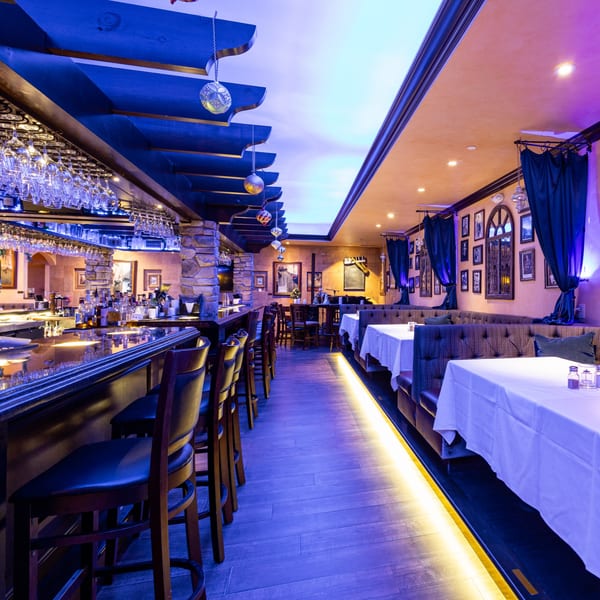 Cafe Vico's dimly lit Italian restaurant interior with a long bar and dining booths.