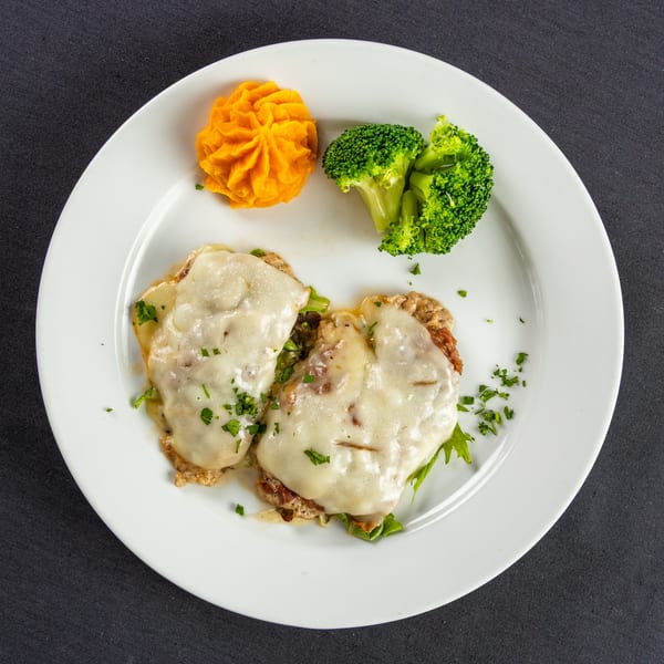 Two cheesy Italian cutlets with a side of mashed sweet potatoes and steamed broccoli on a white plate.