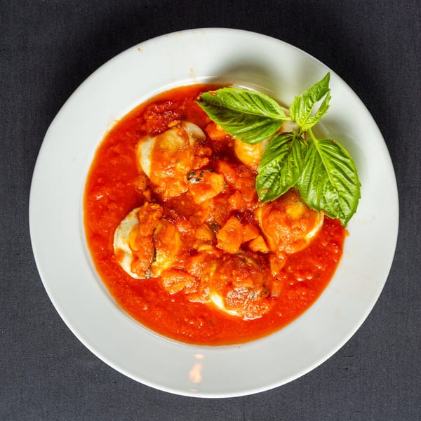 Cafe Vico's Italian ravioli in rich red tomato sauce, garnished with fresh basil leaves.